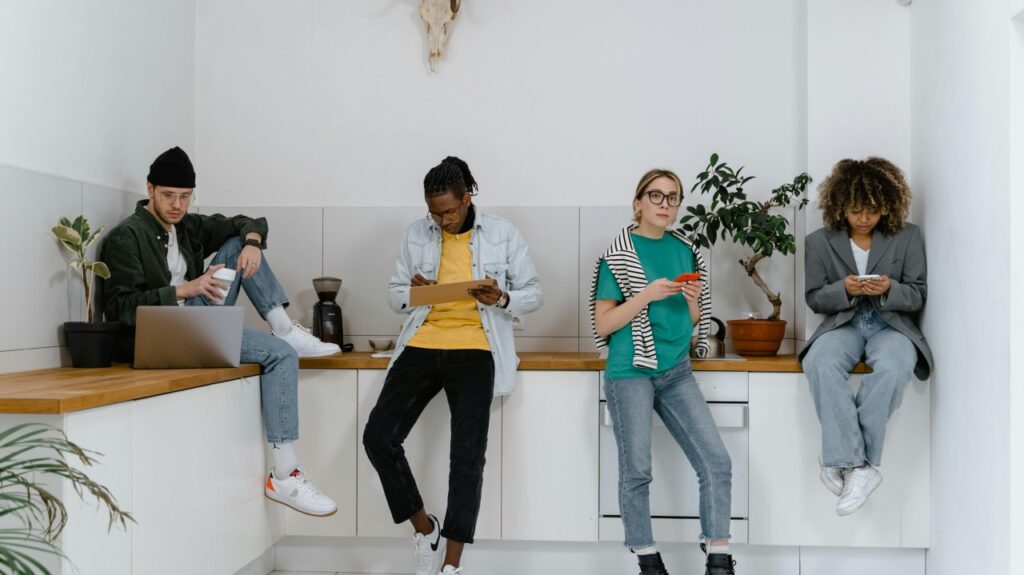 Jovens em uma sala usando computador, tablet e celular
